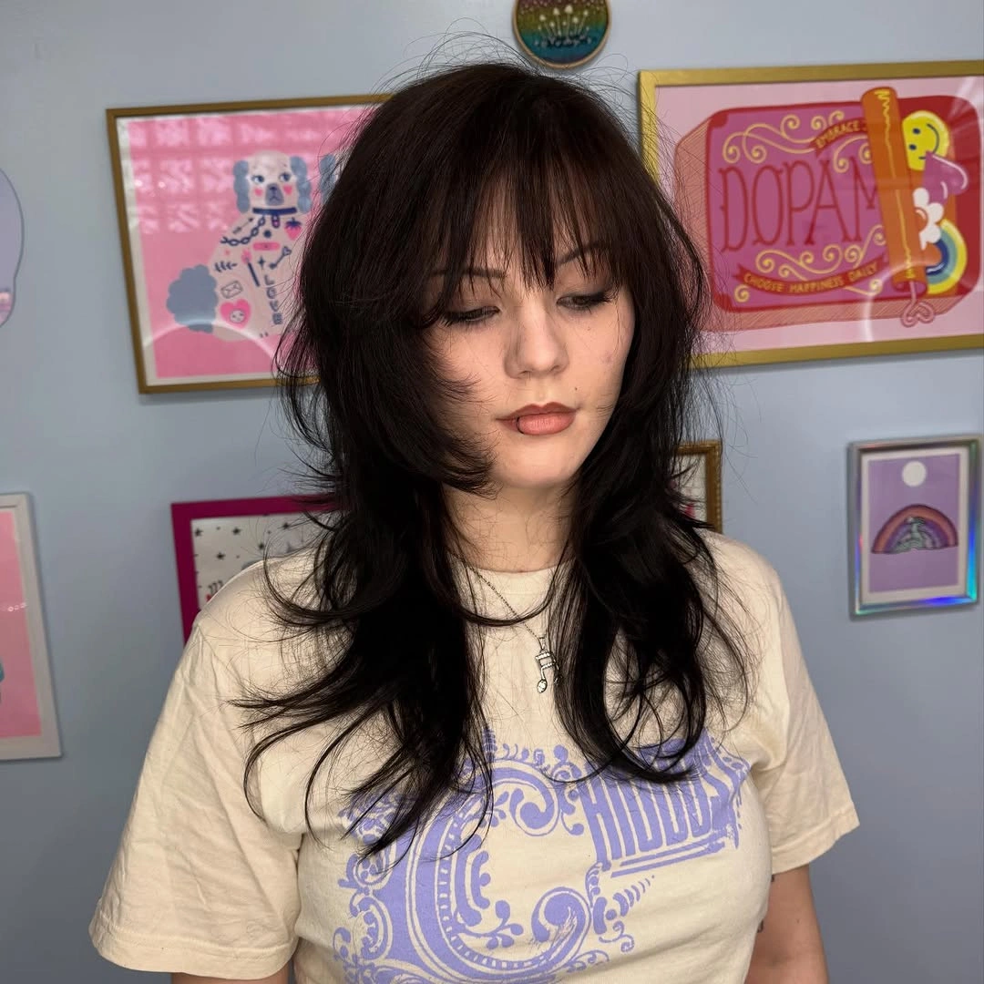 Medium black shag-like haircut with wispy bangs and layered ends