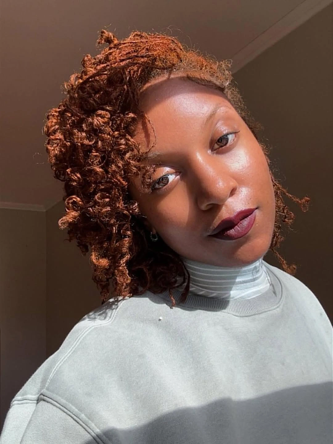 Short copper curls with side-swept volume and forehead tendril