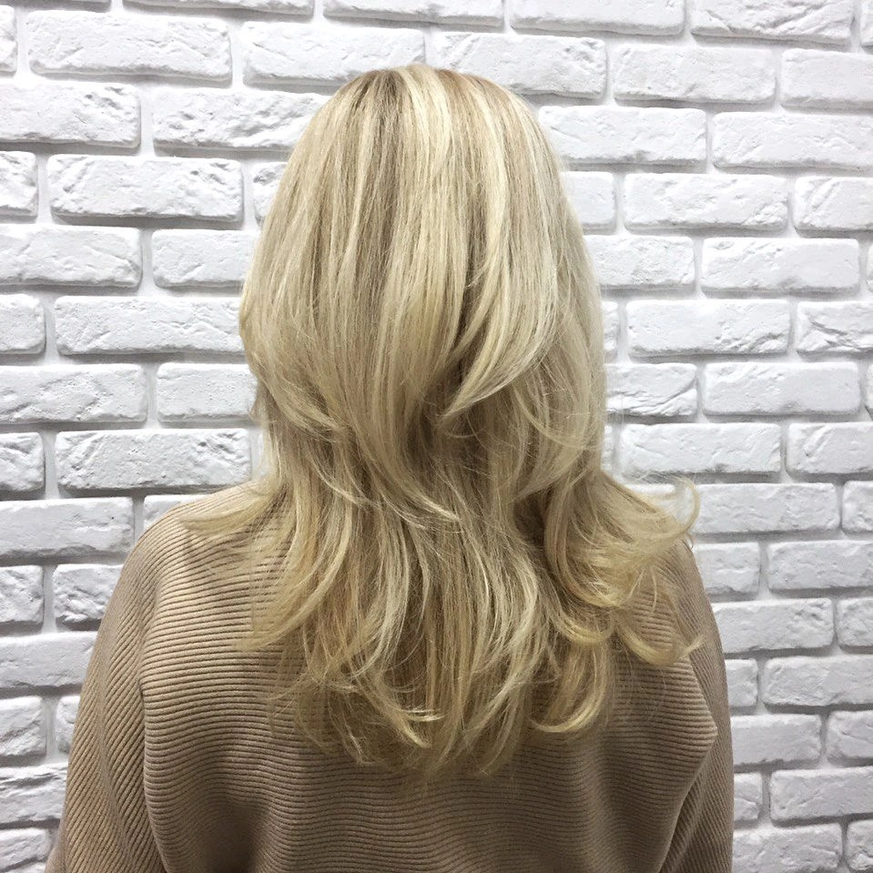 Long blonde layered hair with feathered outward curving ends