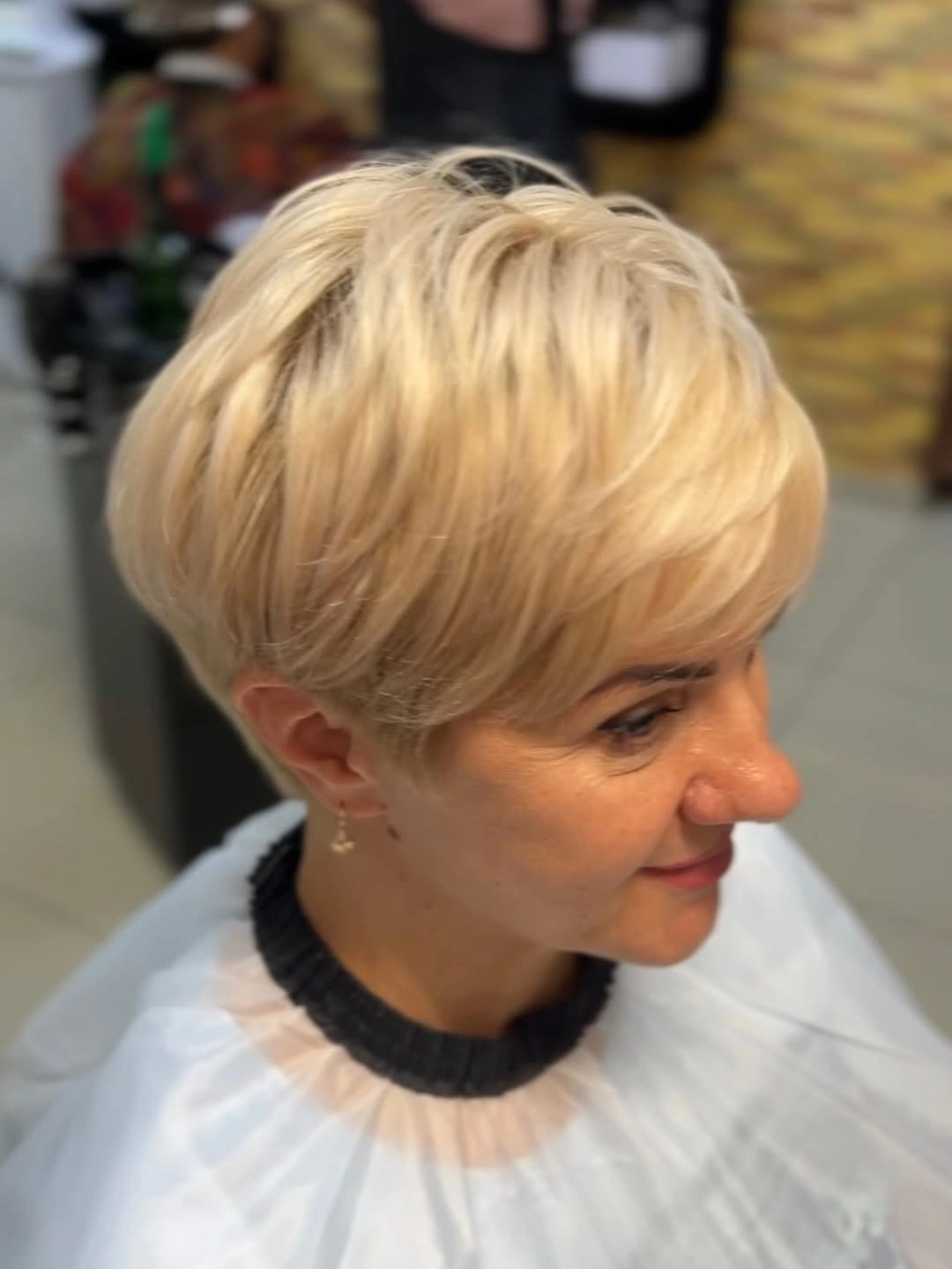 Short blonde pixie with swept layered top and close sides