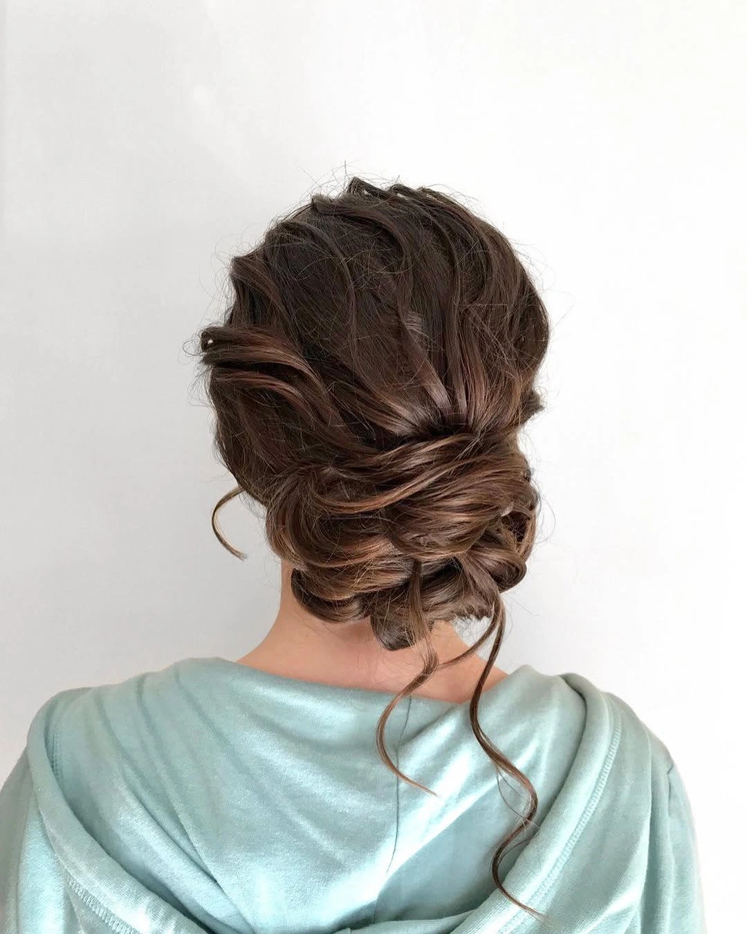 Dark brown low updo with twisted-looking sections and loose strands