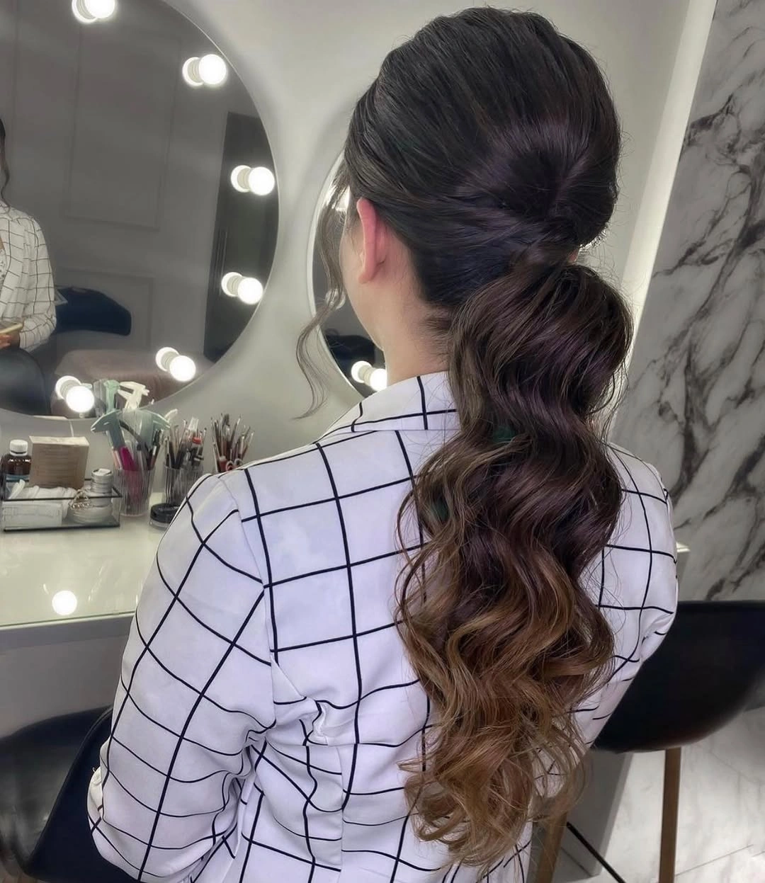 Long brunette low ponytail with gathered base and broad lower waves