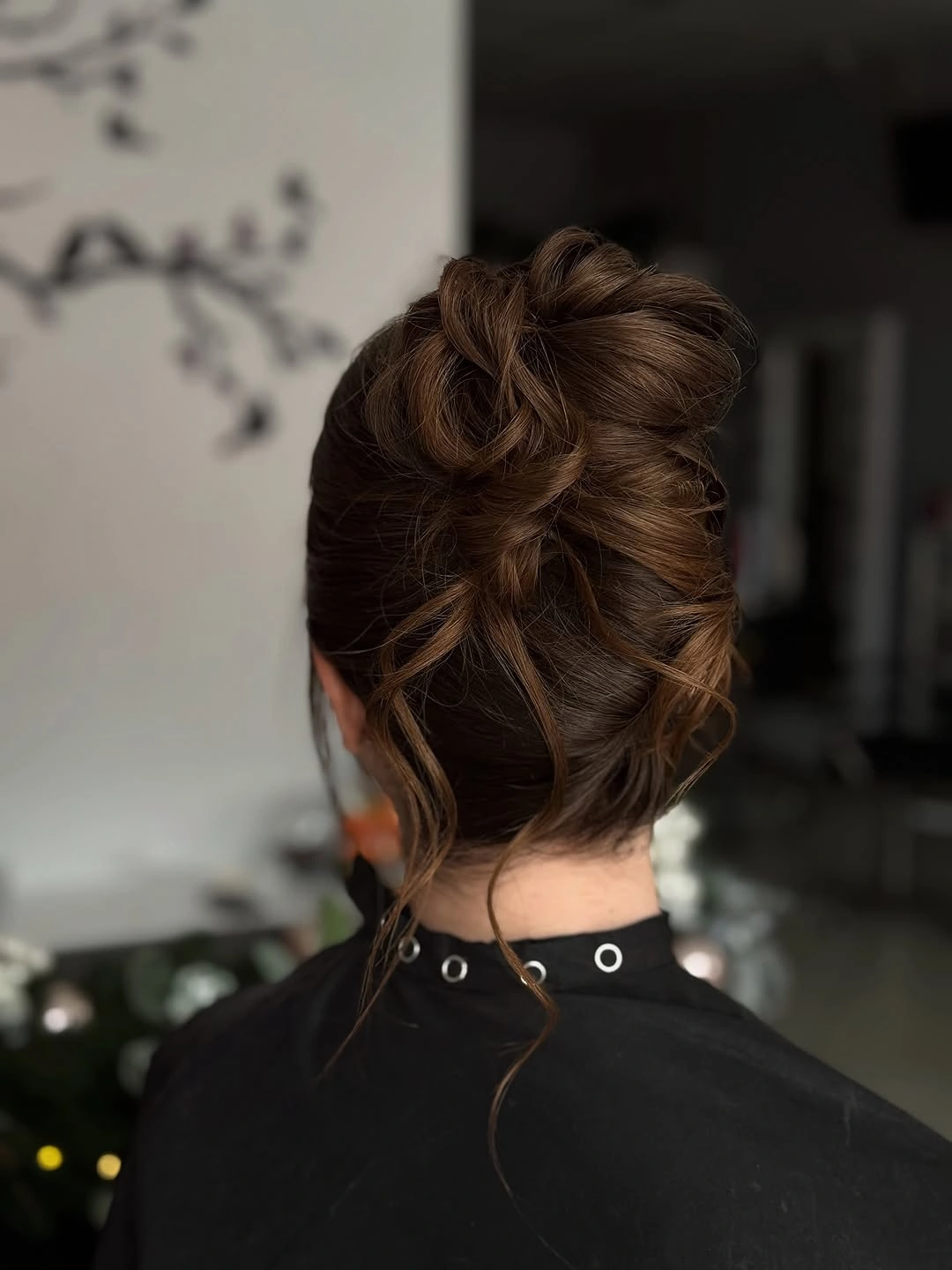 Brown textured updo with overlapping loops and loose nape tendrils