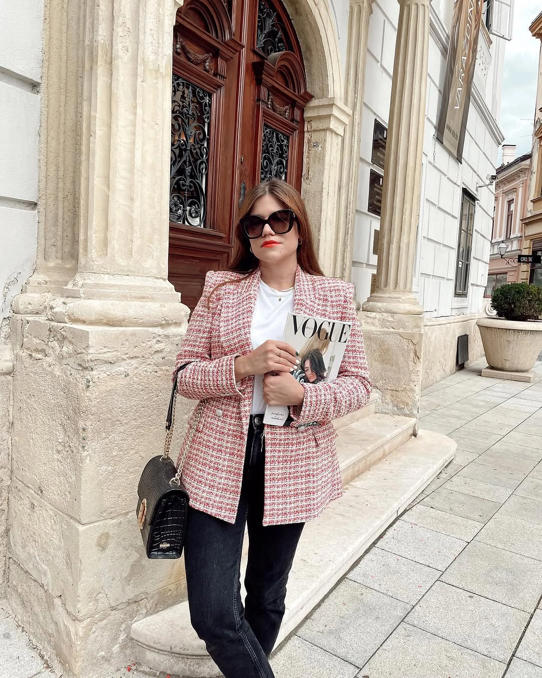 Woman on city street in white top layer, jeans, and pale boots