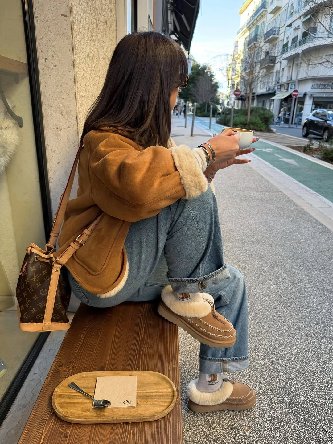 Woman in red oversized sweater, dark jeans, sneakers, and sunglasses