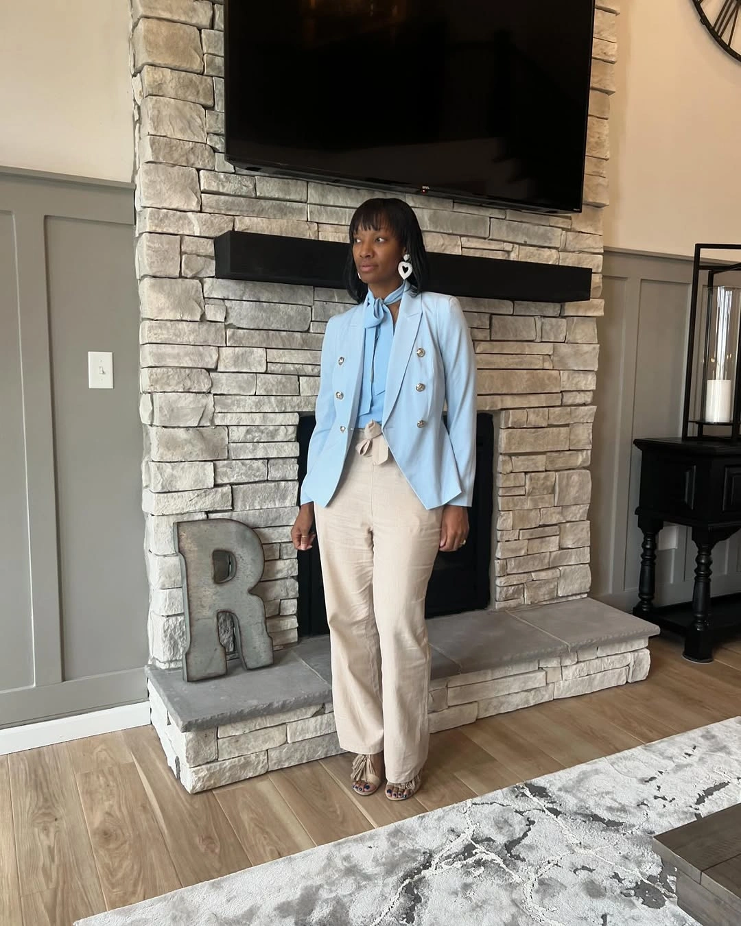 Pale blue double-breasted blazer with black top and beige trousers