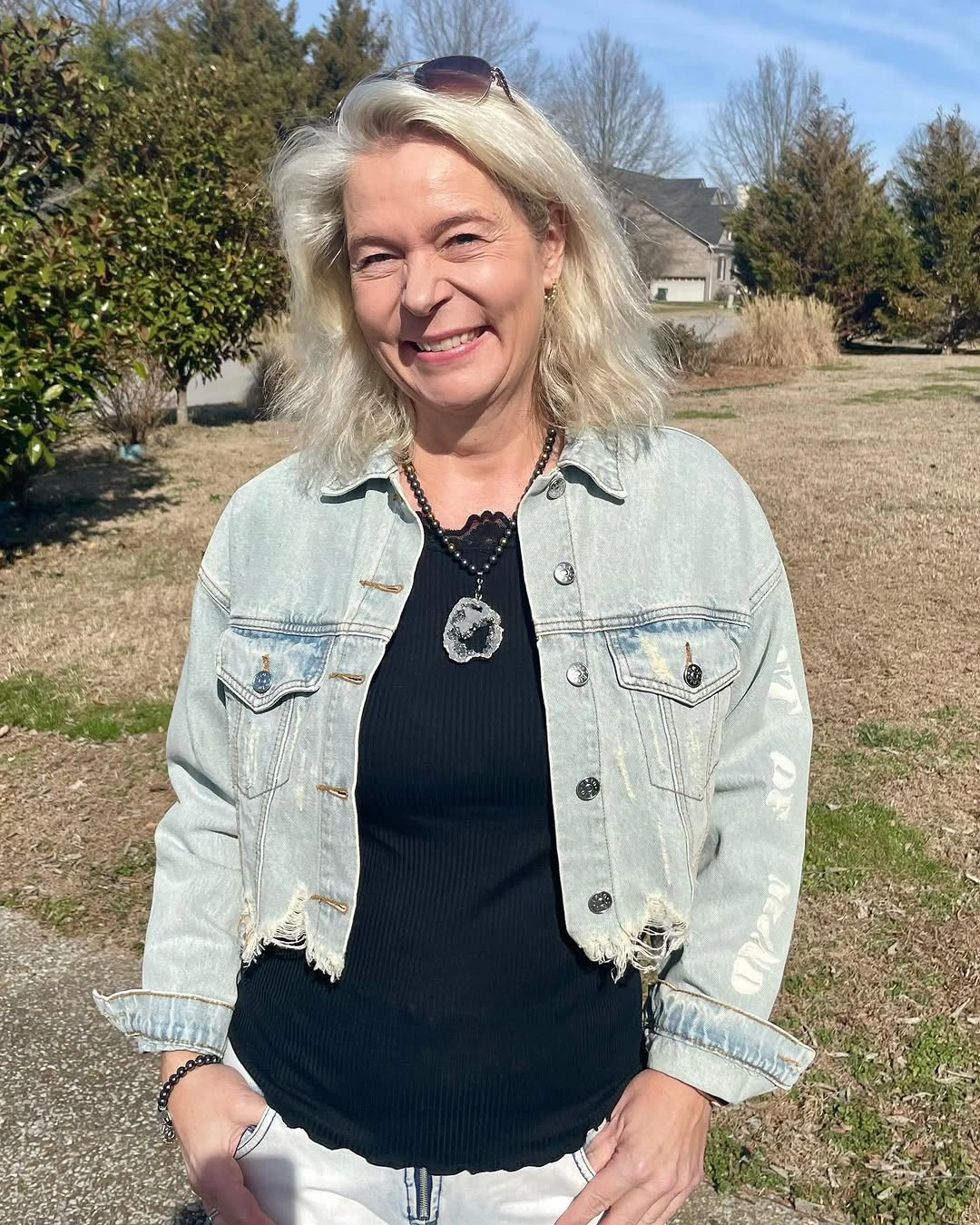 Pale cropped denim jacket over black top and white pants