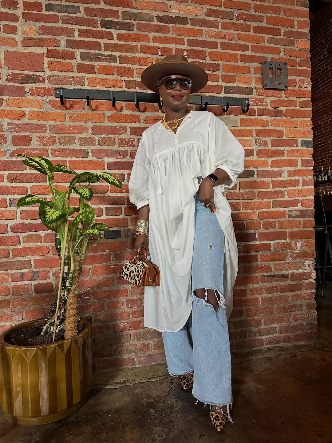 White long tunic over ripped jeans with hat and leopard shoes