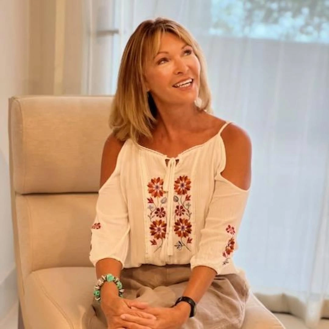 White off-shoulder blouse with red floral embroidery and bracelets