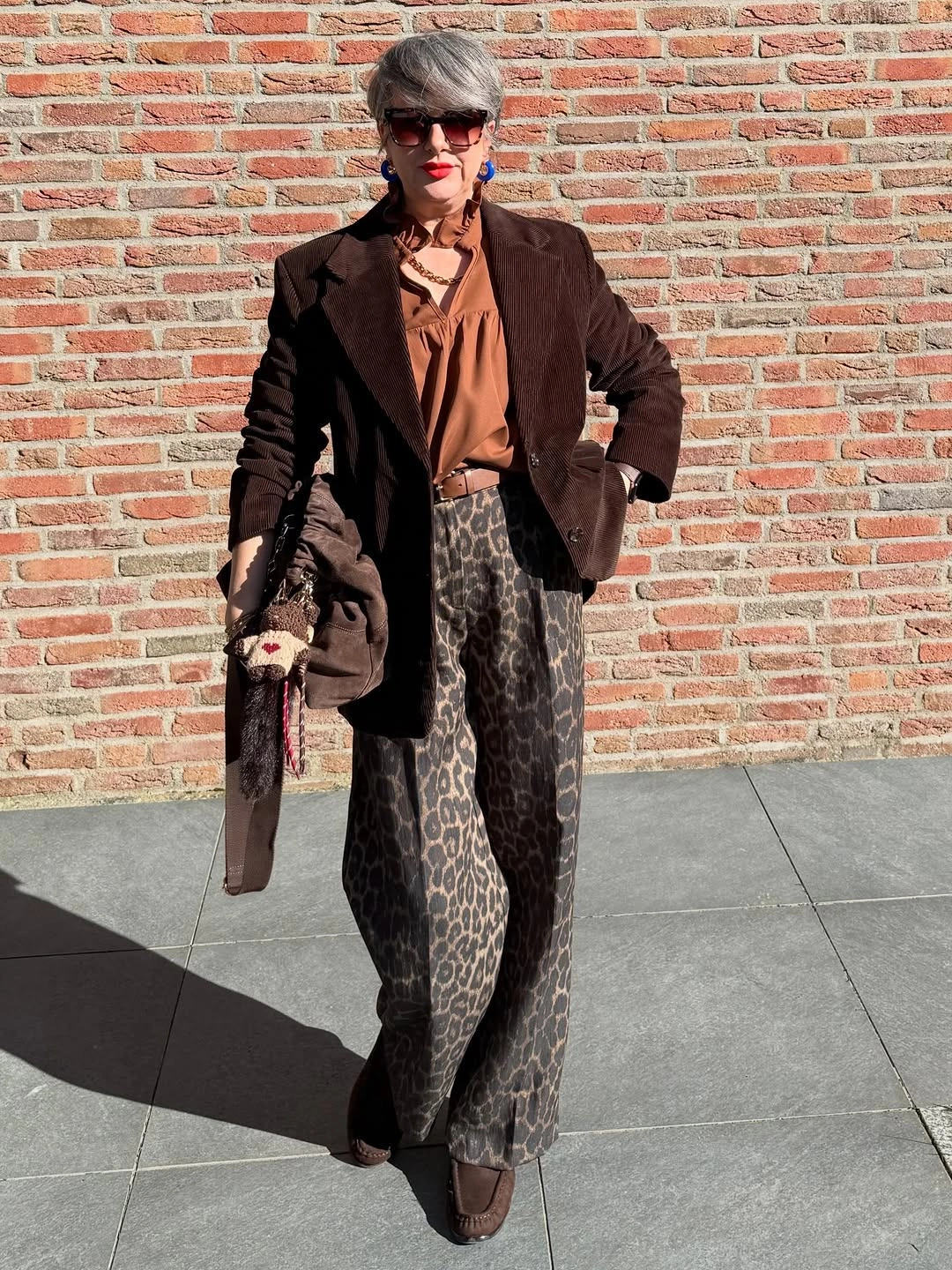 Woman in brown blazer, rust blouse and leopard trousers