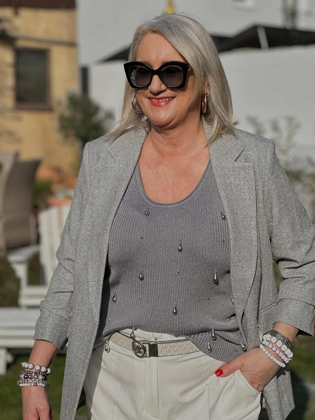 Woman in gray blazer, embellished top and light trousers