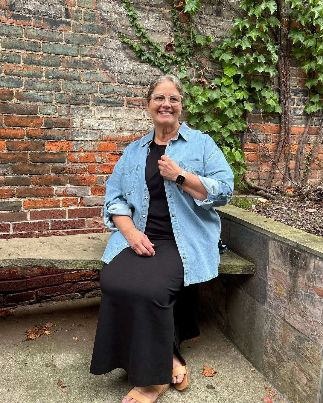 Woman in open denim shirt over black column outfit