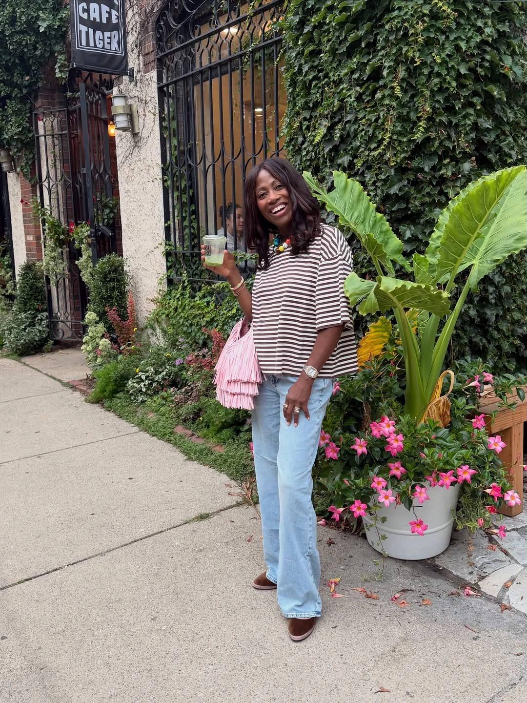 Woman in boxy striped top, flared jeans and pink bag