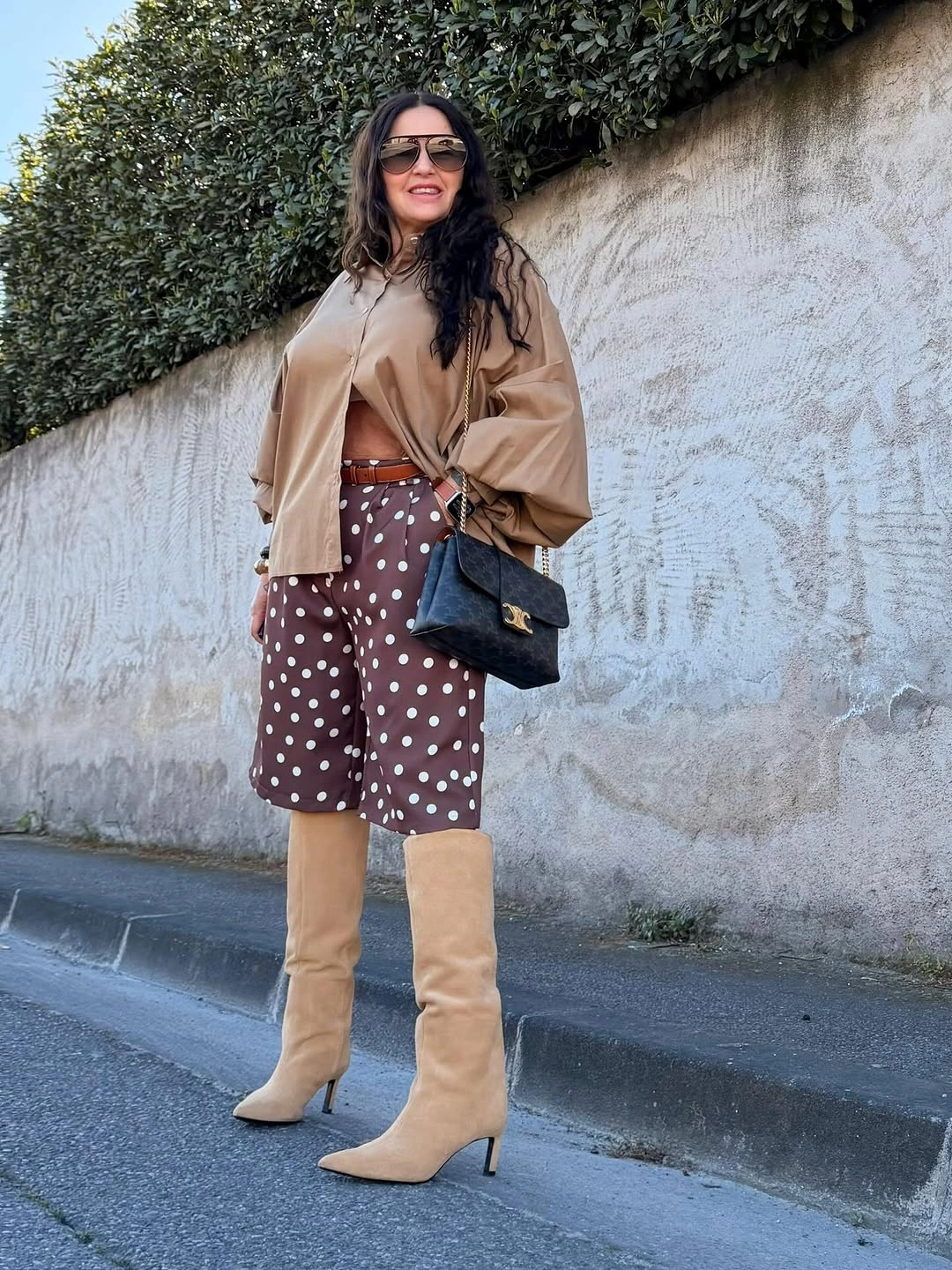 Woman in tan draped top, dotted culottes and beige boots