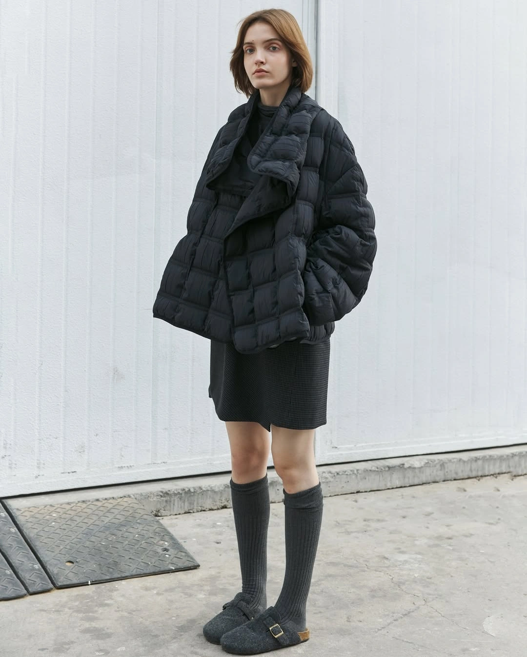 Black oversized puffer with dark skirt and tall gray socks