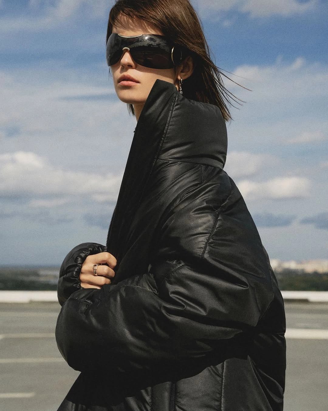 Black high collar puffer with oversized visor sunglasses