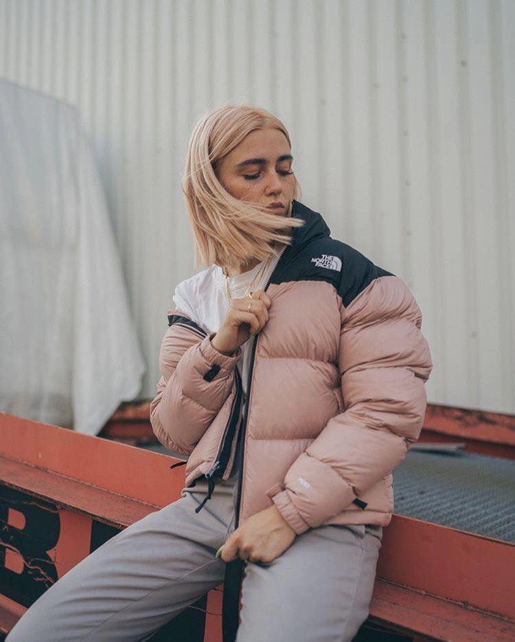 Blush pink puffer with black shoulder panel and gray pants