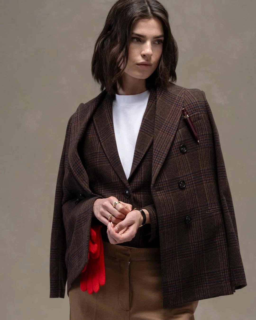 Brown checked blazers layered over white top with red gloves