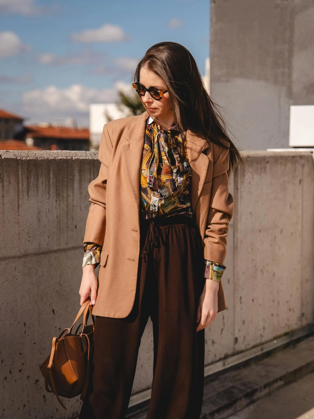 Camel blazer with patterned blouse, brown trousers, and handbag