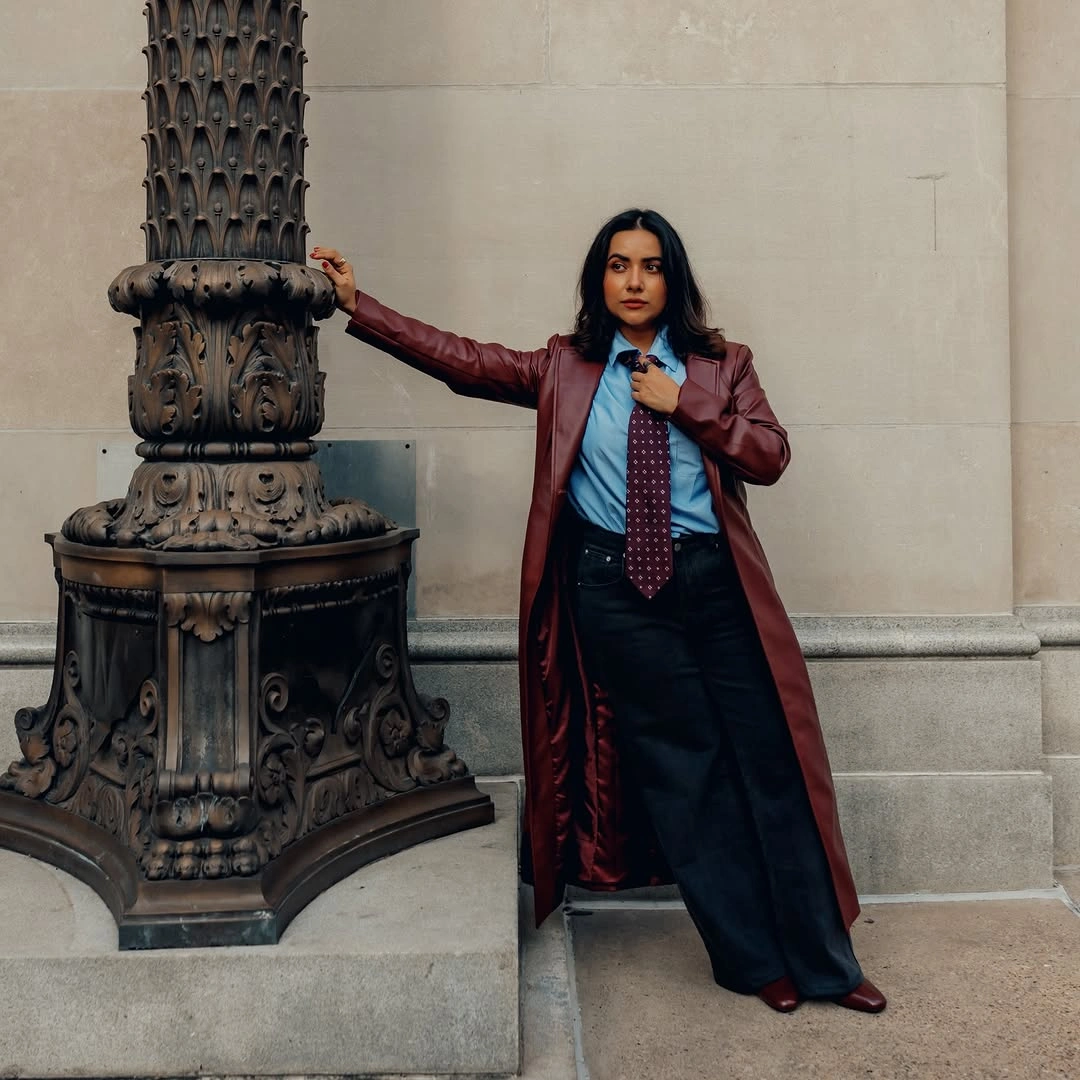 Burgundy long coat with blue shirt, tie, and black trousers