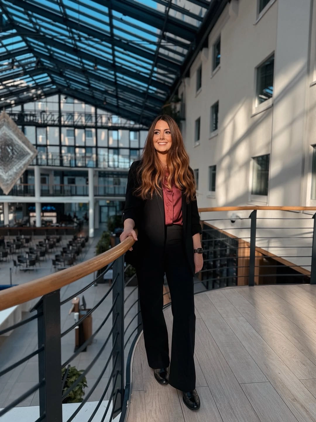 Black blazer with rose blouse, flared trousers, and black shoes