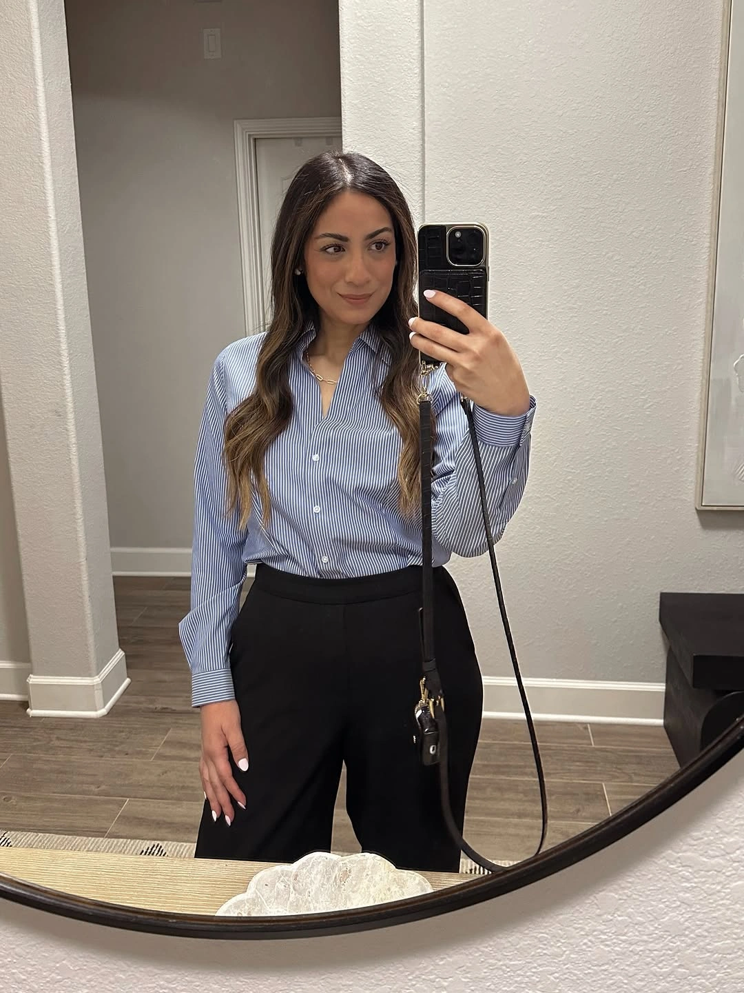Blue striped button-up tucked into high-waisted black trousers