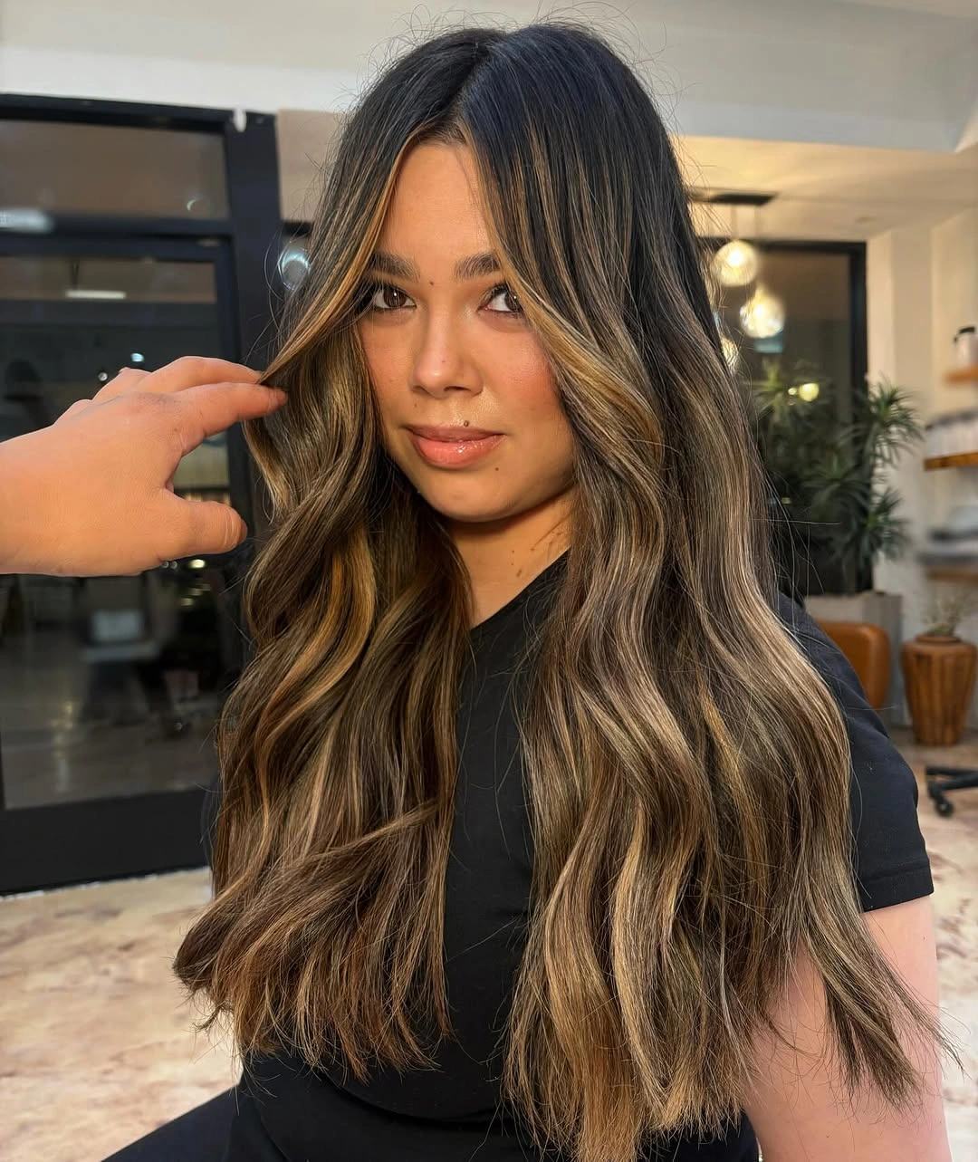 deep brunette waves with golden face-framing pieces and lower highlights