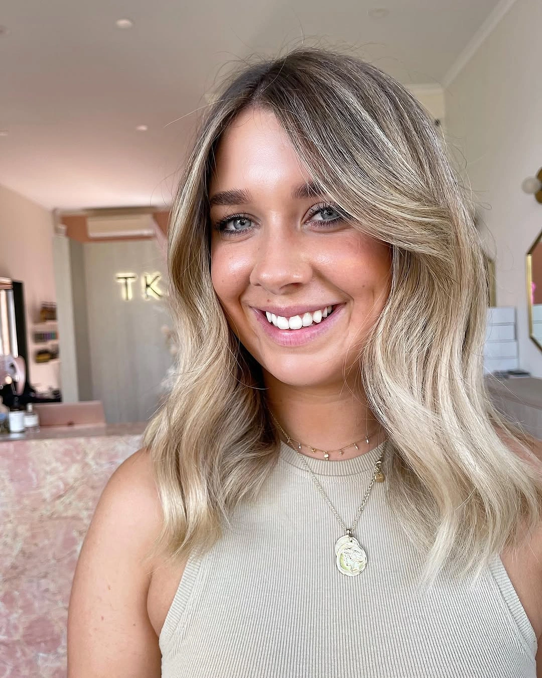 Medium blonde hair with ash ribbons and darker roots