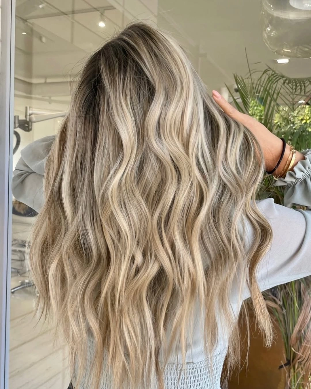 Very long sandy blonde waves with darker roots and bright ribbons