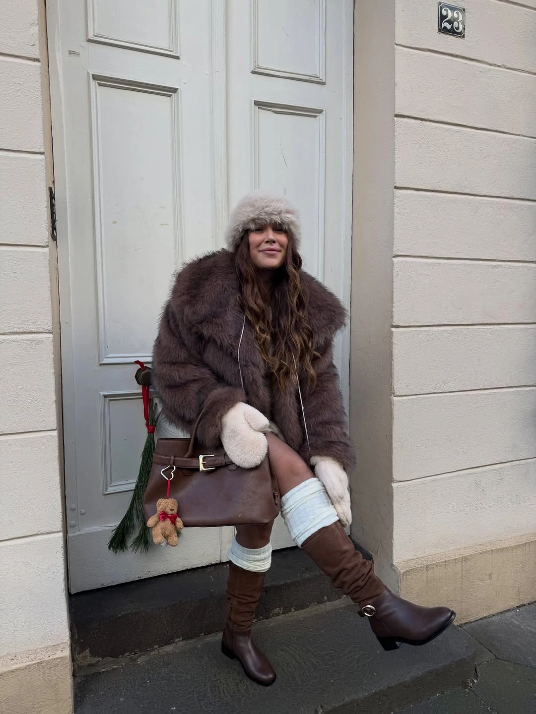 dark brown faux fur jacket with tall burgundy boots and handbag