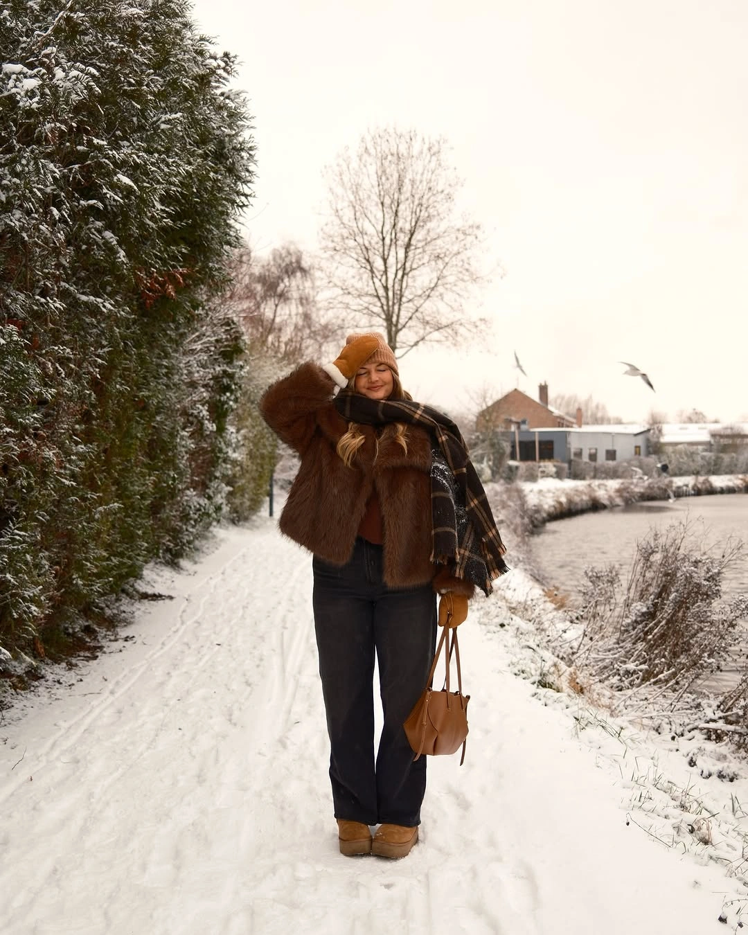 brown textured jacket black trousers and bright orange beanie