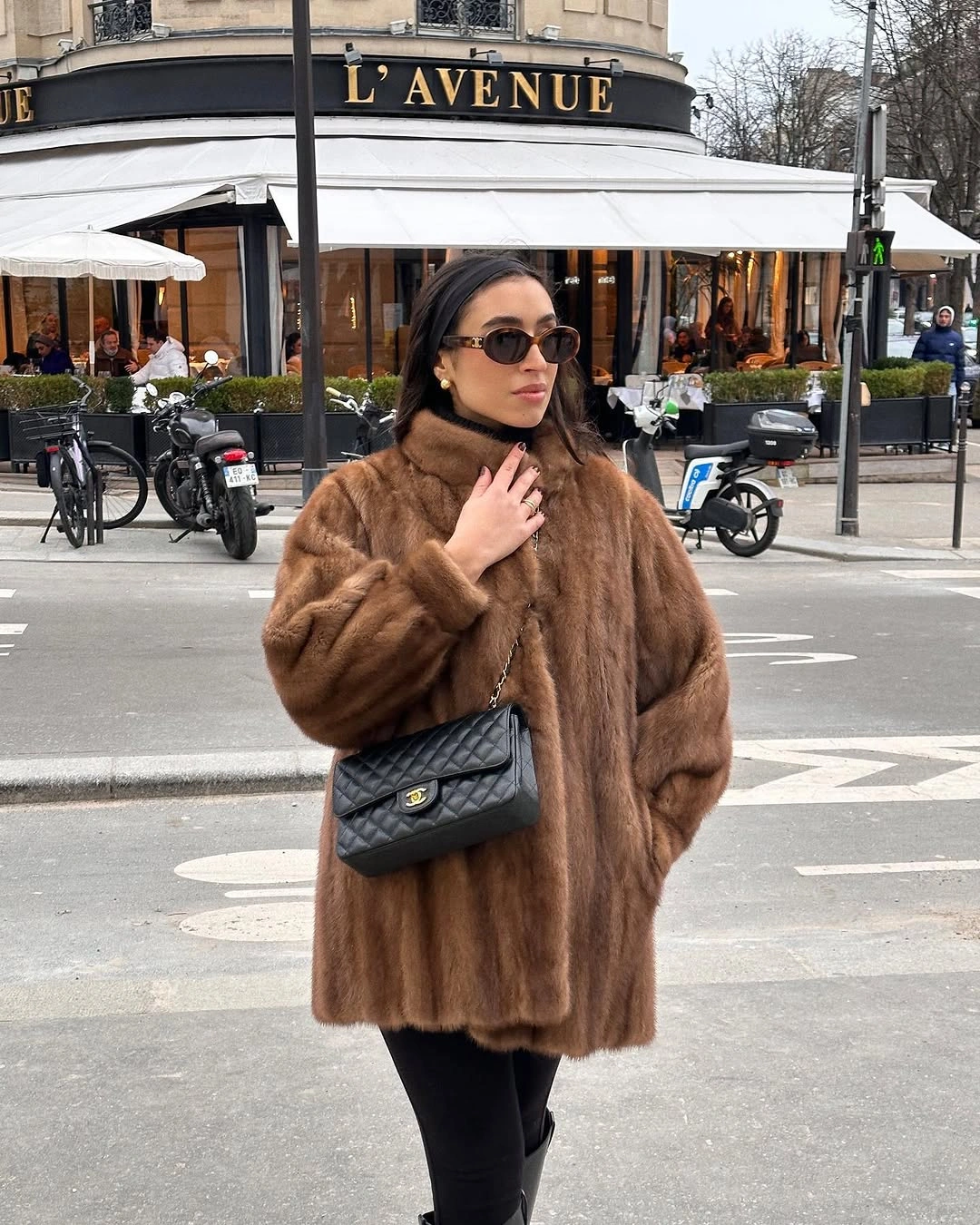 camel faux fur coat with black trousers sunglasses and quilted black bag
