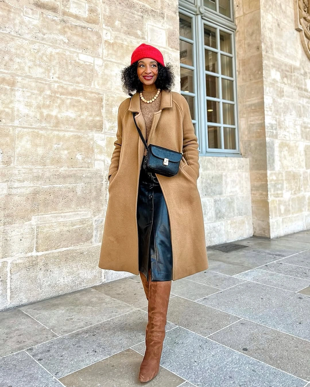 camel long coat with red beanie tall brown boots and cream knit