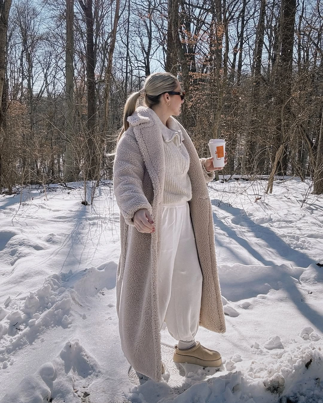 Pale long coat with cream top, white pants, and beige shoes