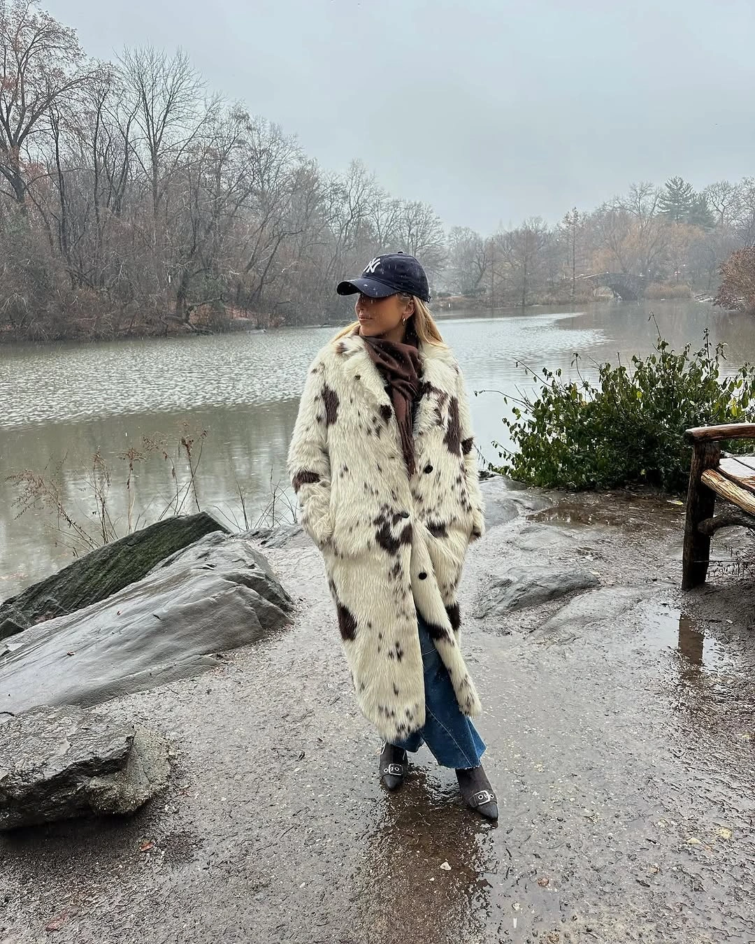 Long cream spotted coat with jeans, cap, gloves, and dark shoes