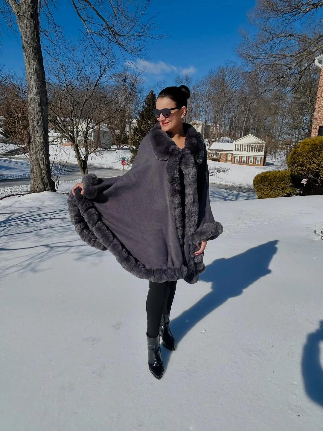 Gray cape-like wrap with dark trim and glossy black boots