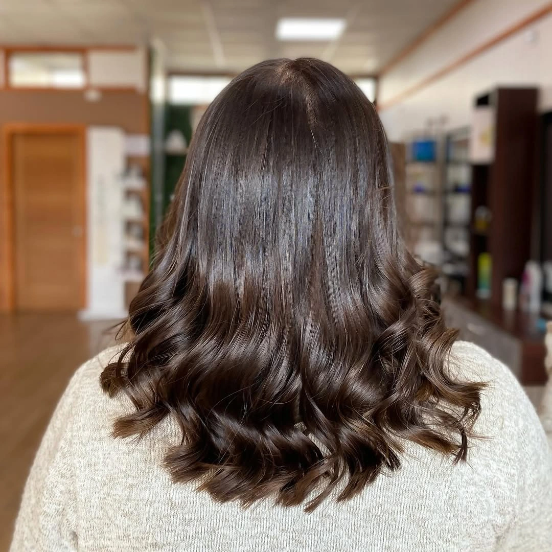 Dark brunette shoulder-length hair with loose curls at the ends