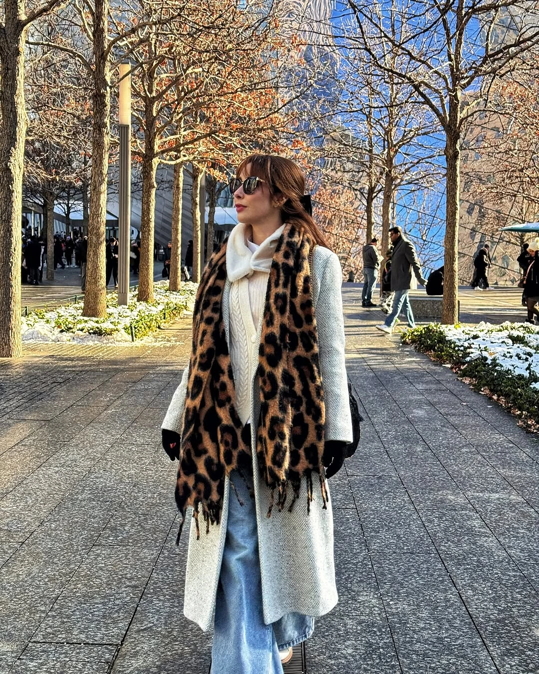 Woman in gray coat, leopard scarf, wide jeans, and black gloves