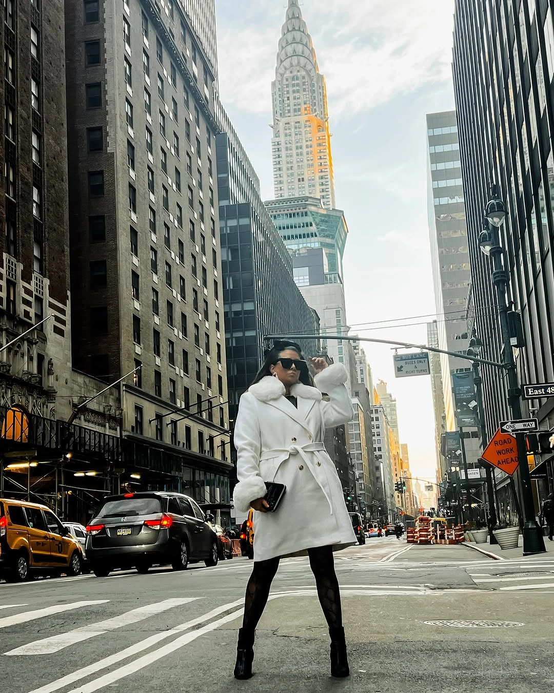 Woman in belted white coat, black tights, and knee-high boots