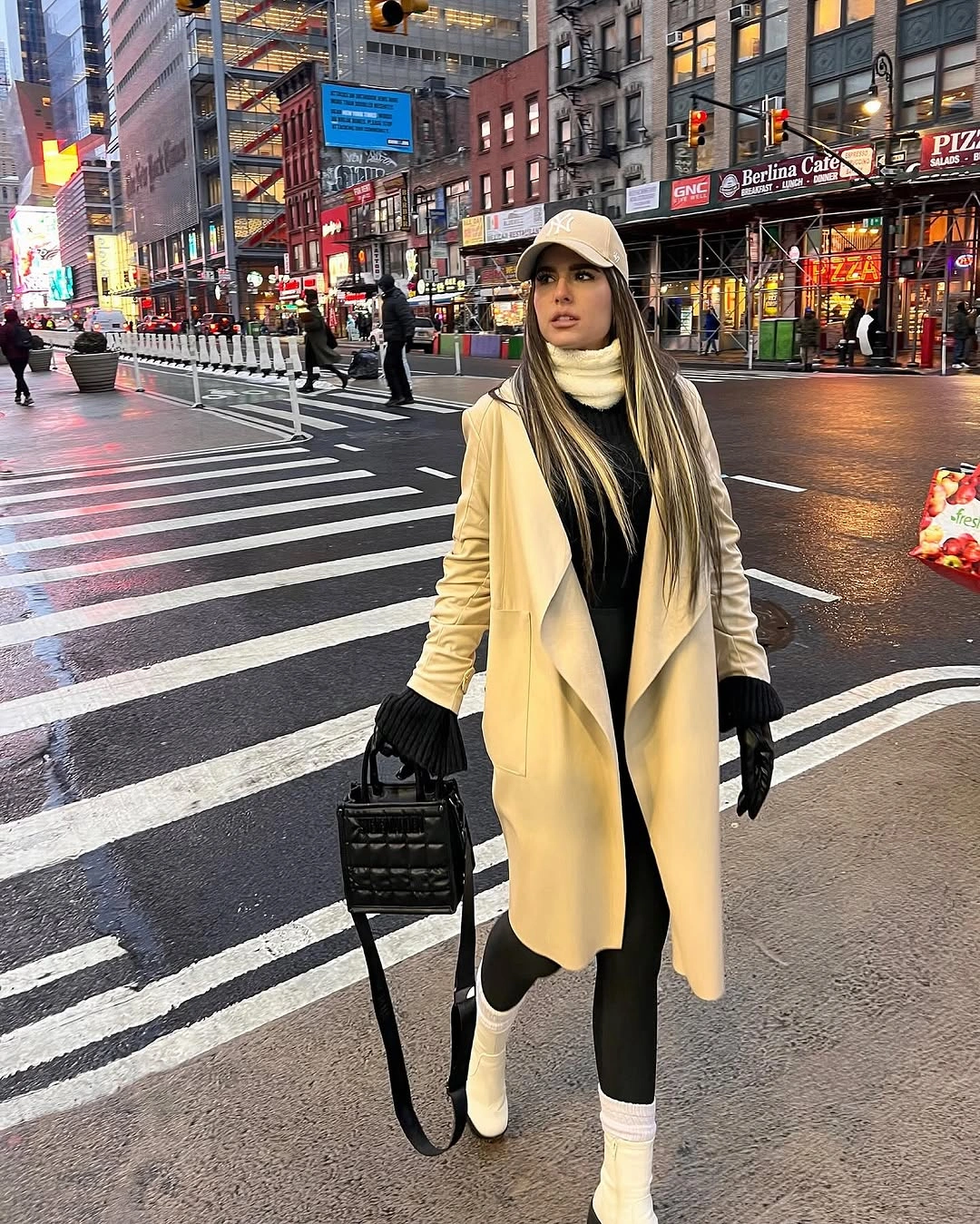 Woman in cream coat, black leggings, cap, gloves, and white boots