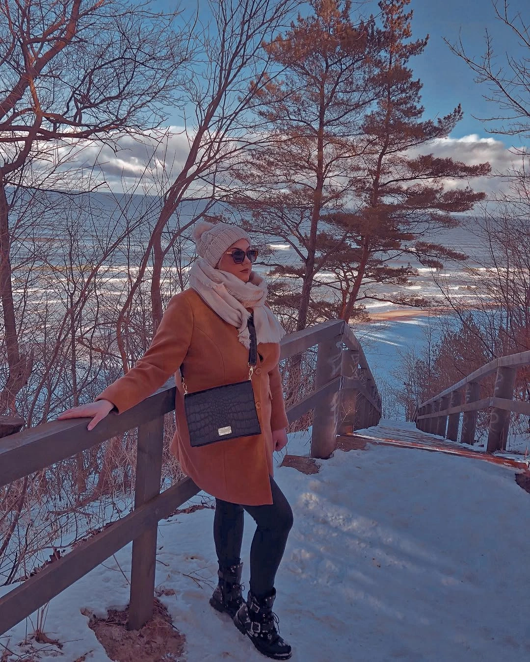 Rust coat with white wrap, black bag and snowy water