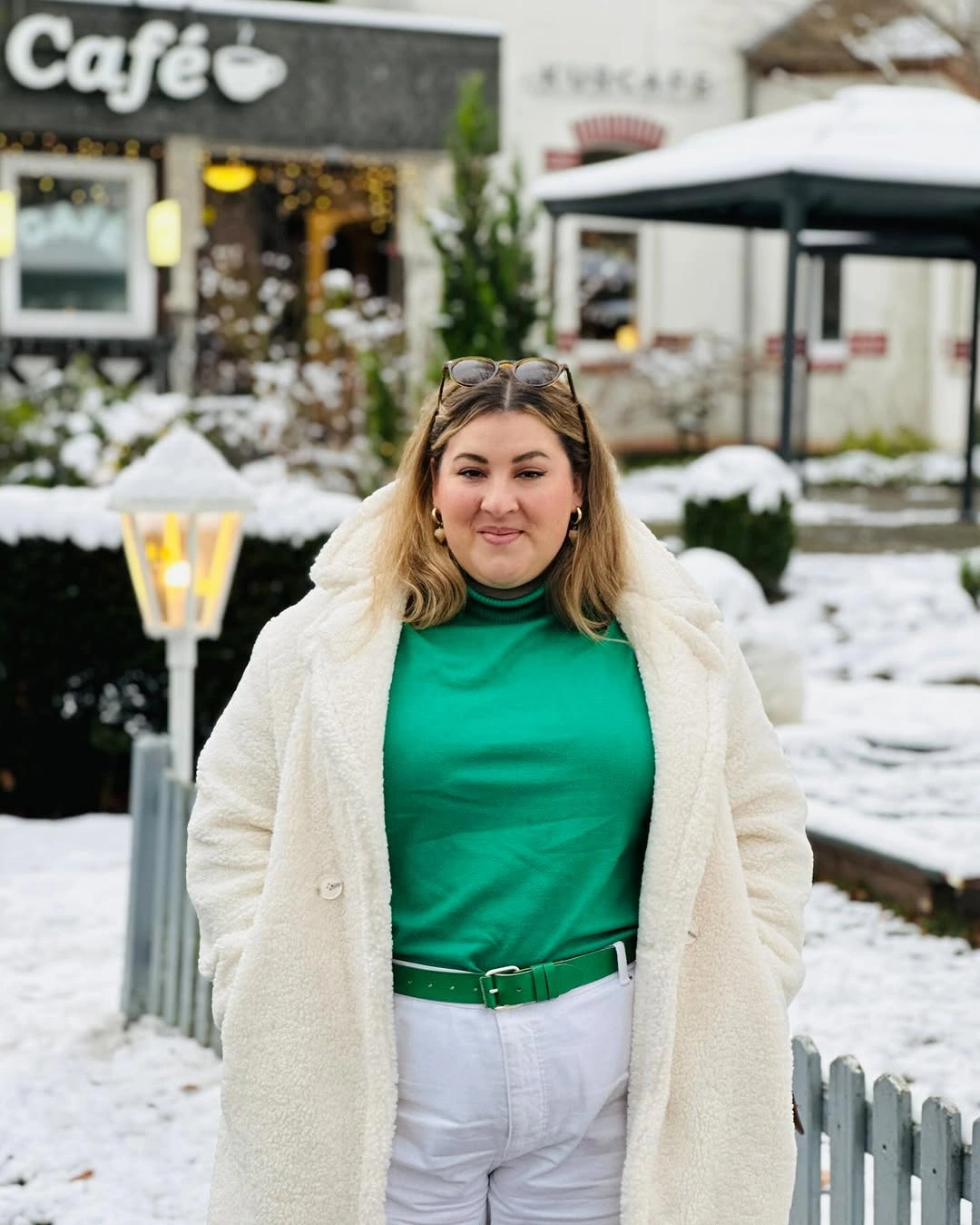 White coat and pants with green turtleneck and belt