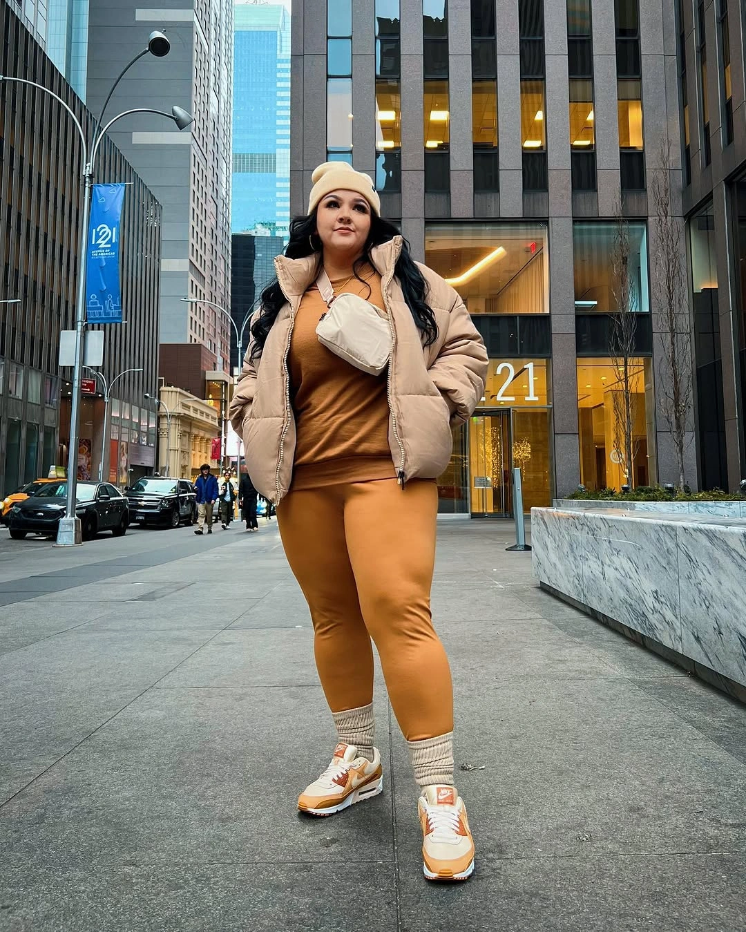 Tan puffer, camel layers, cream beanie and white sneakers with orange details