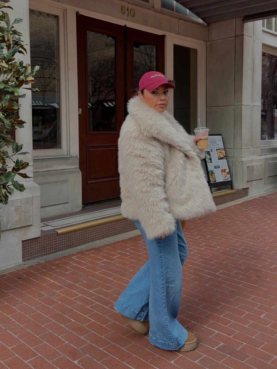 Cream fur-like jacket with pink cap and flared jeans
