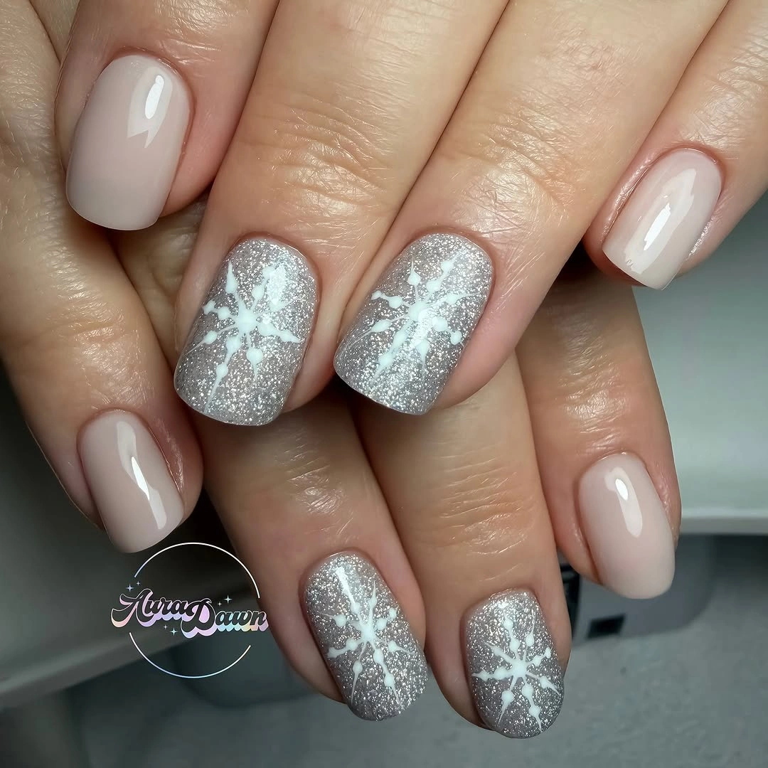 Short rounded neutral nails with silver glitter snowflakes