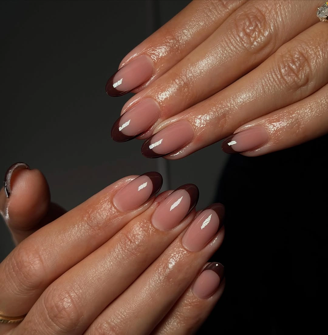 Nude almond nails with deep brown or black French tips