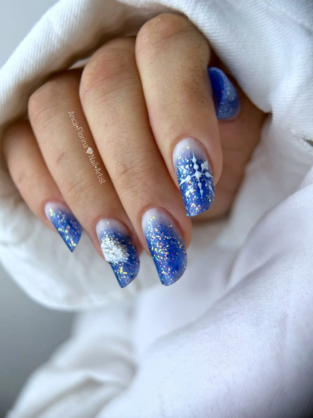 Almond nails with cobalt glitter gradient and white snowflakes