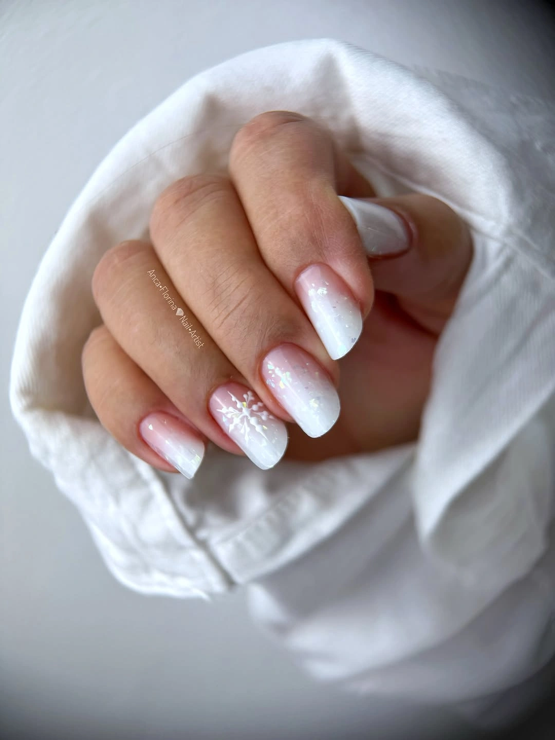 Milky white almond nails with a single snowflake accent
