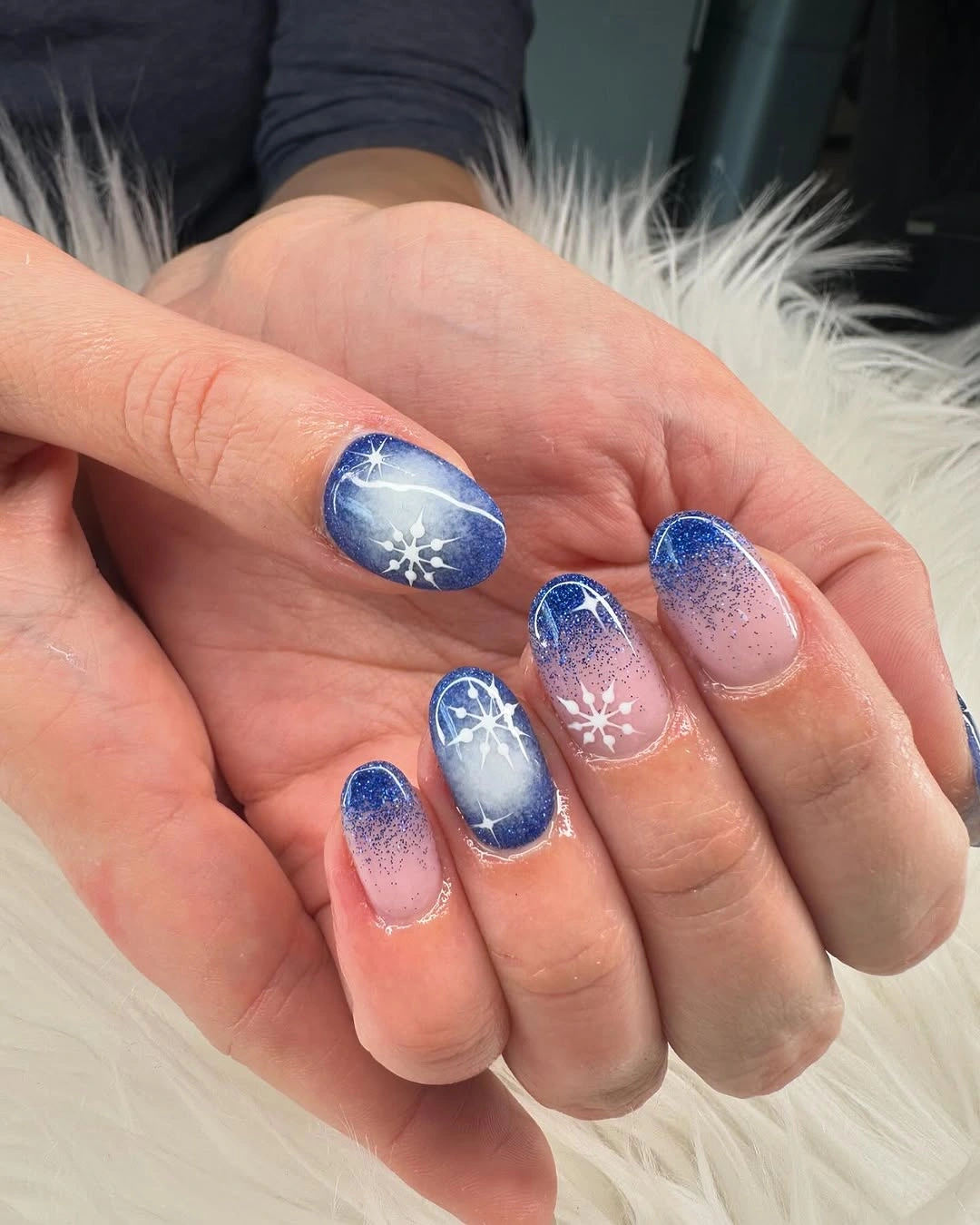 Short rounded blue nails with snowflakes and starburst accents