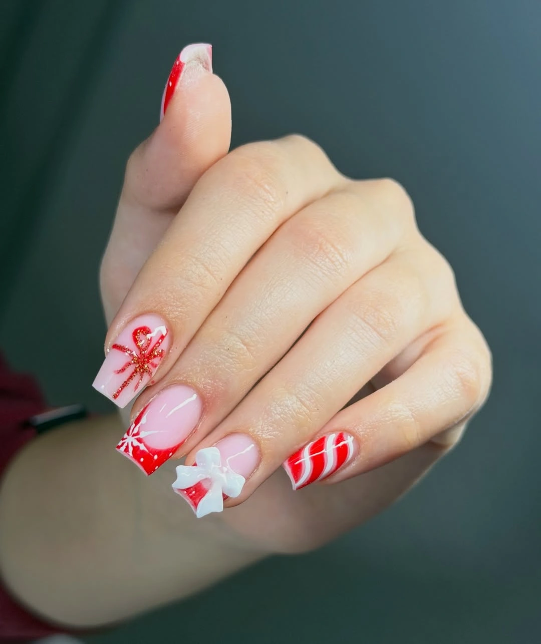 Pink square nails with red tips, stripes and white bow
